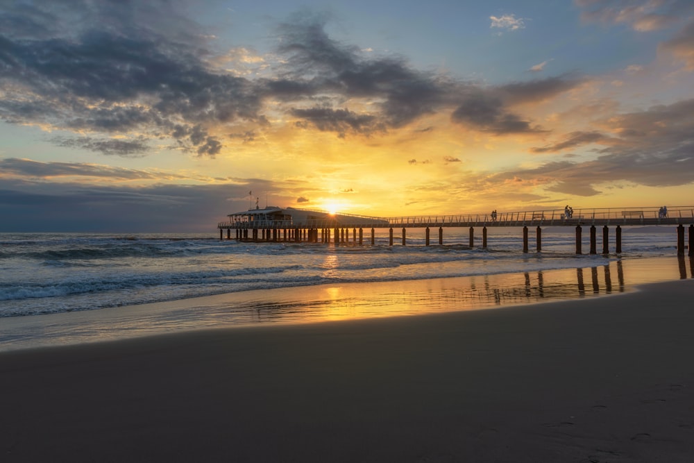 El sol se está poniendo sobre el océano con un muelle en la distancia