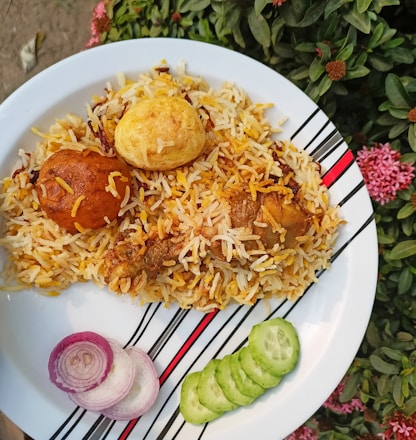 A vibrant platter of steaming hot biryani garnished with fresh herbs and boiled eggs.