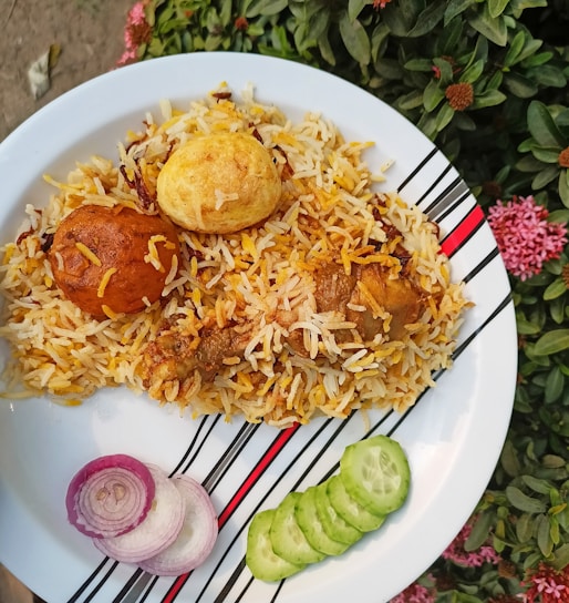 A steaming plate of Kolkata-style biryani garnished with boiled eggs and fresh coriander.