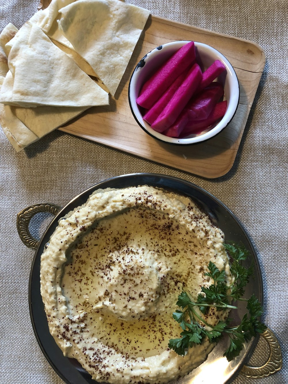 a bowl of hummus, pita chips and a bowl of radishes