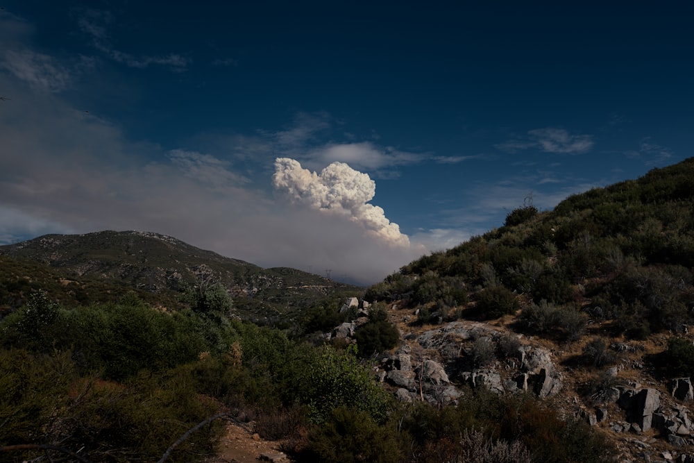 Una nuvola di fumo si alza sopra una collina rocciosa