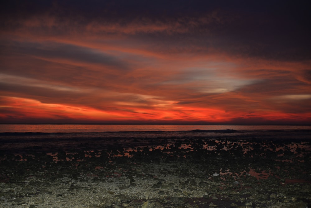 a red and orange sunset over the ocean