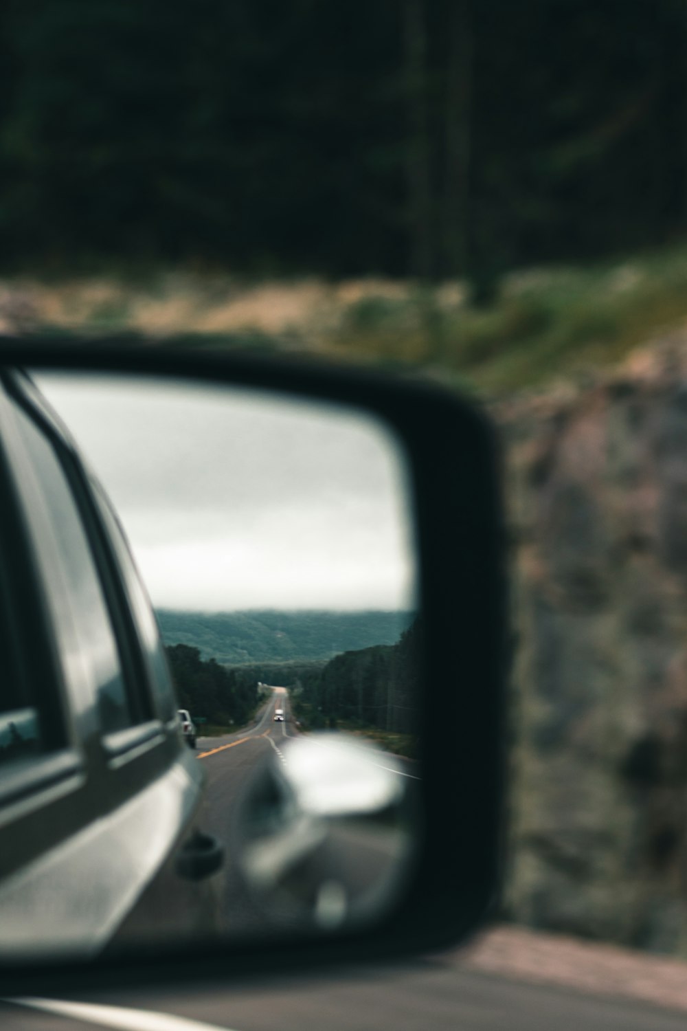 a car's side view mirror on the side of a road