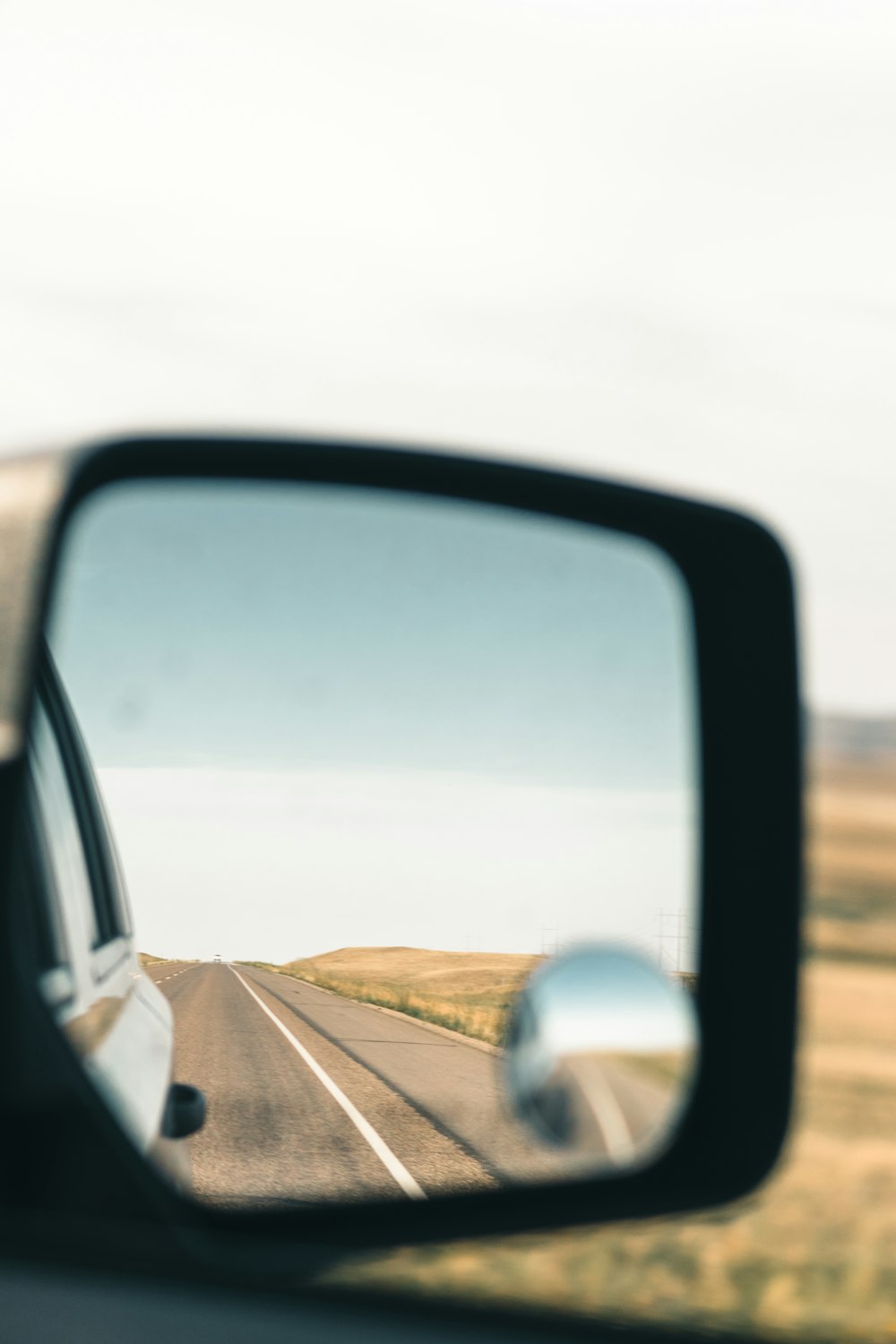 a car's side view mirror reflecting a road