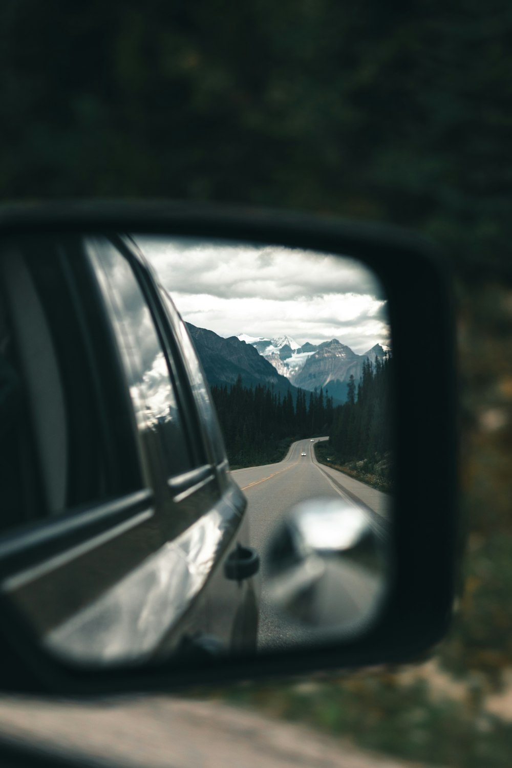 a car's side view mirror reflecting a mountain range