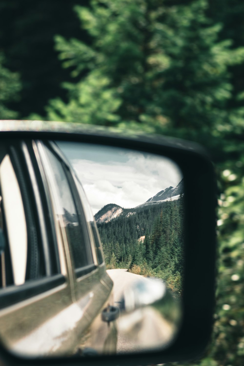 a car's side view mirror reflecting a mountain scene