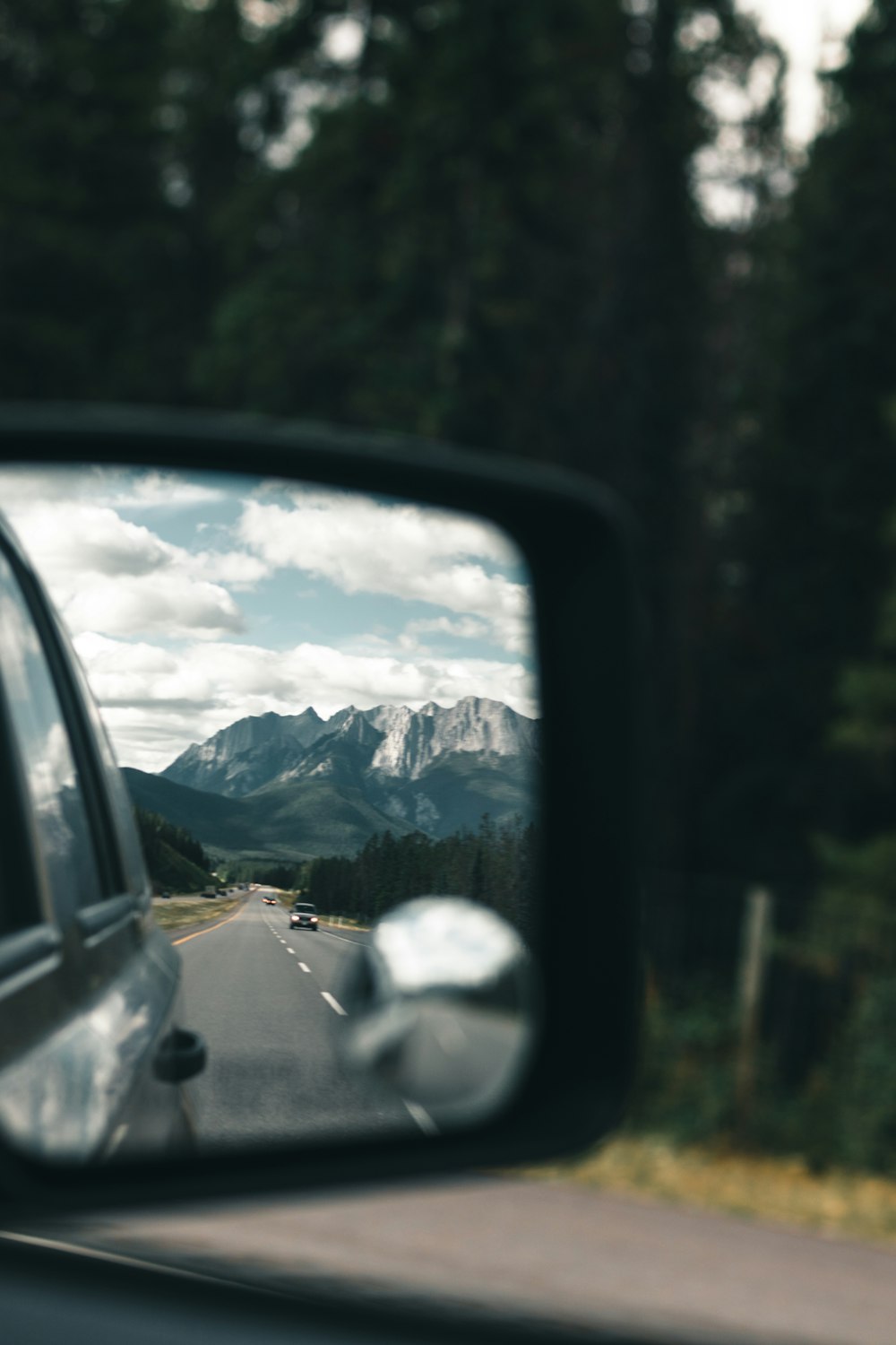 a car's side view mirror with mountains in the background