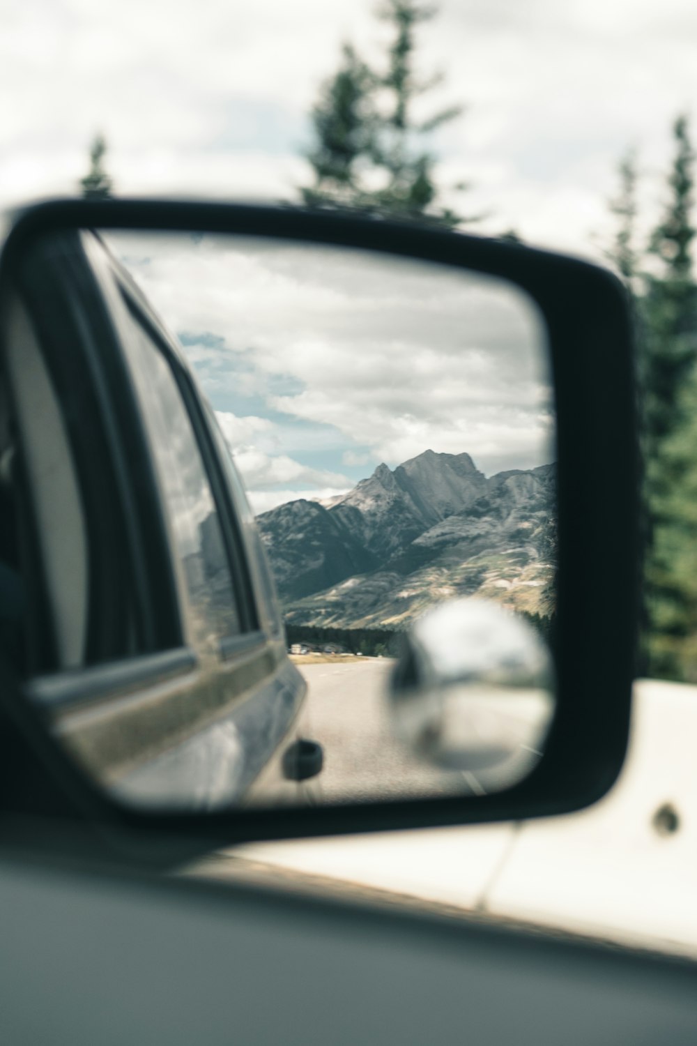 a car's side view mirror with mountains in the background