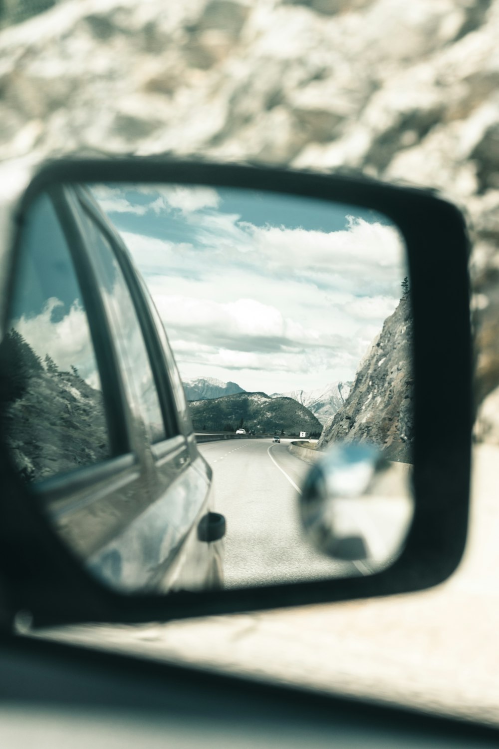 a side view mirror on a car reflecting a mountain