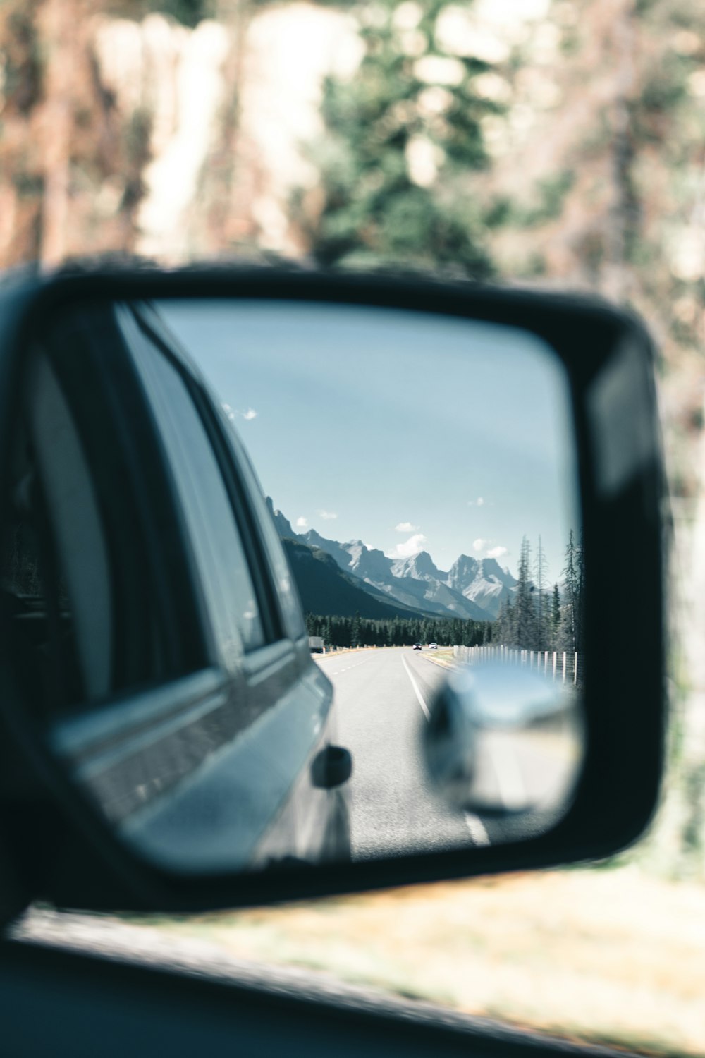 a car's side view mirror with mountains in the background