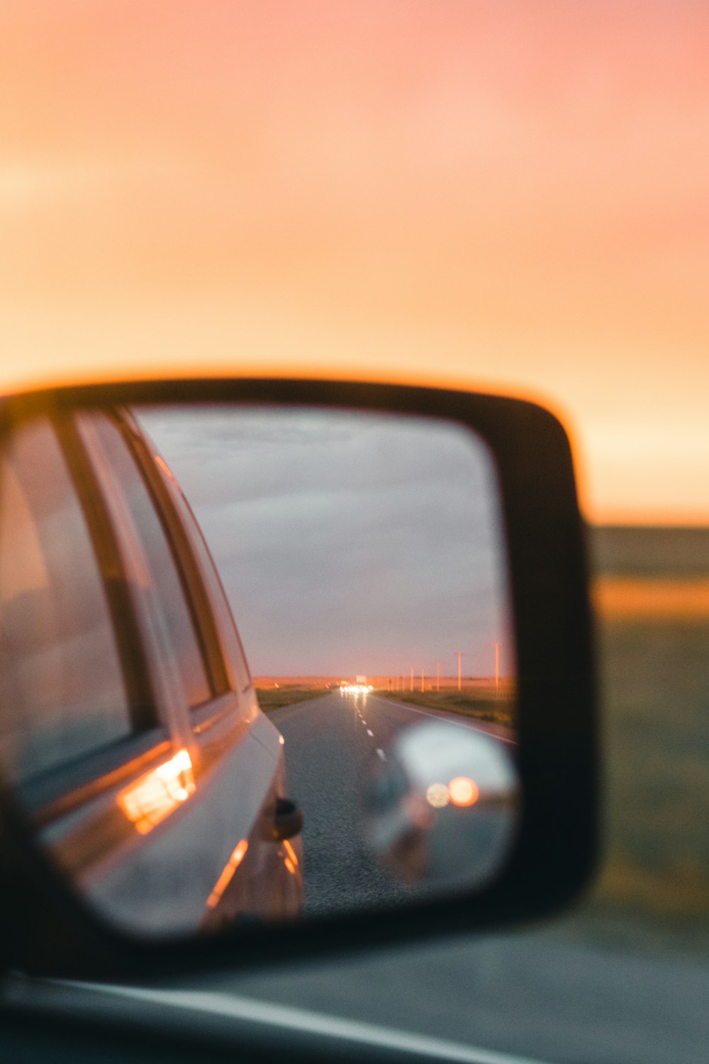 a rear view mirror on a car with a sunset in the background