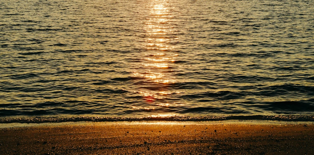 the sun is setting over the water at the beach