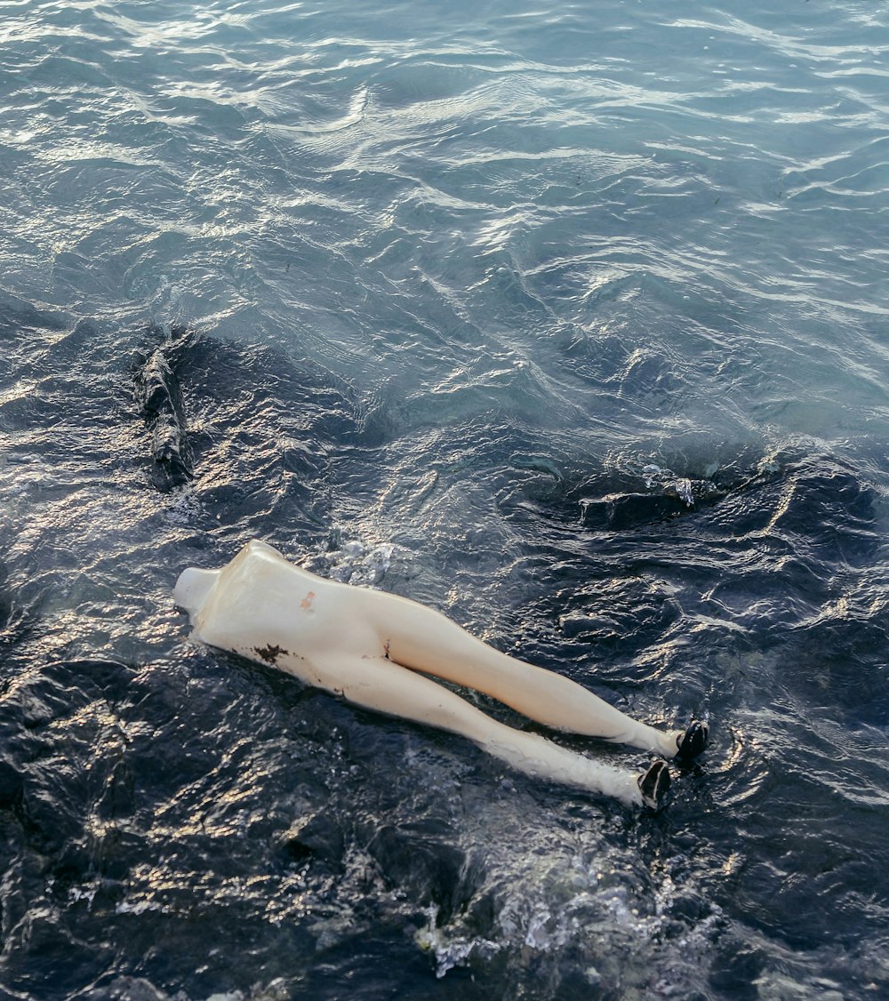 a white mannequin laying in the water