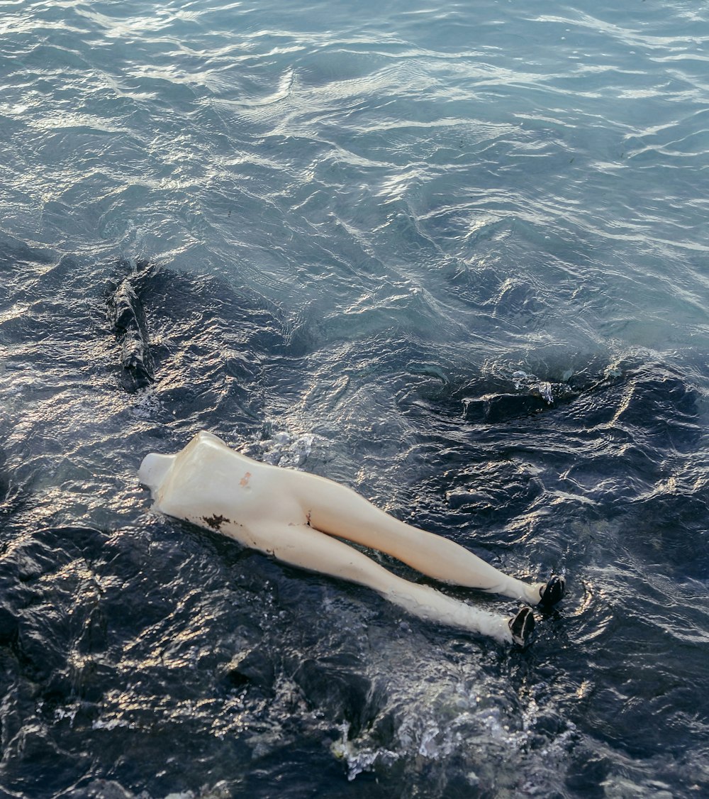 eine weiße Schaufensterpuppe, die im Wasser liegt