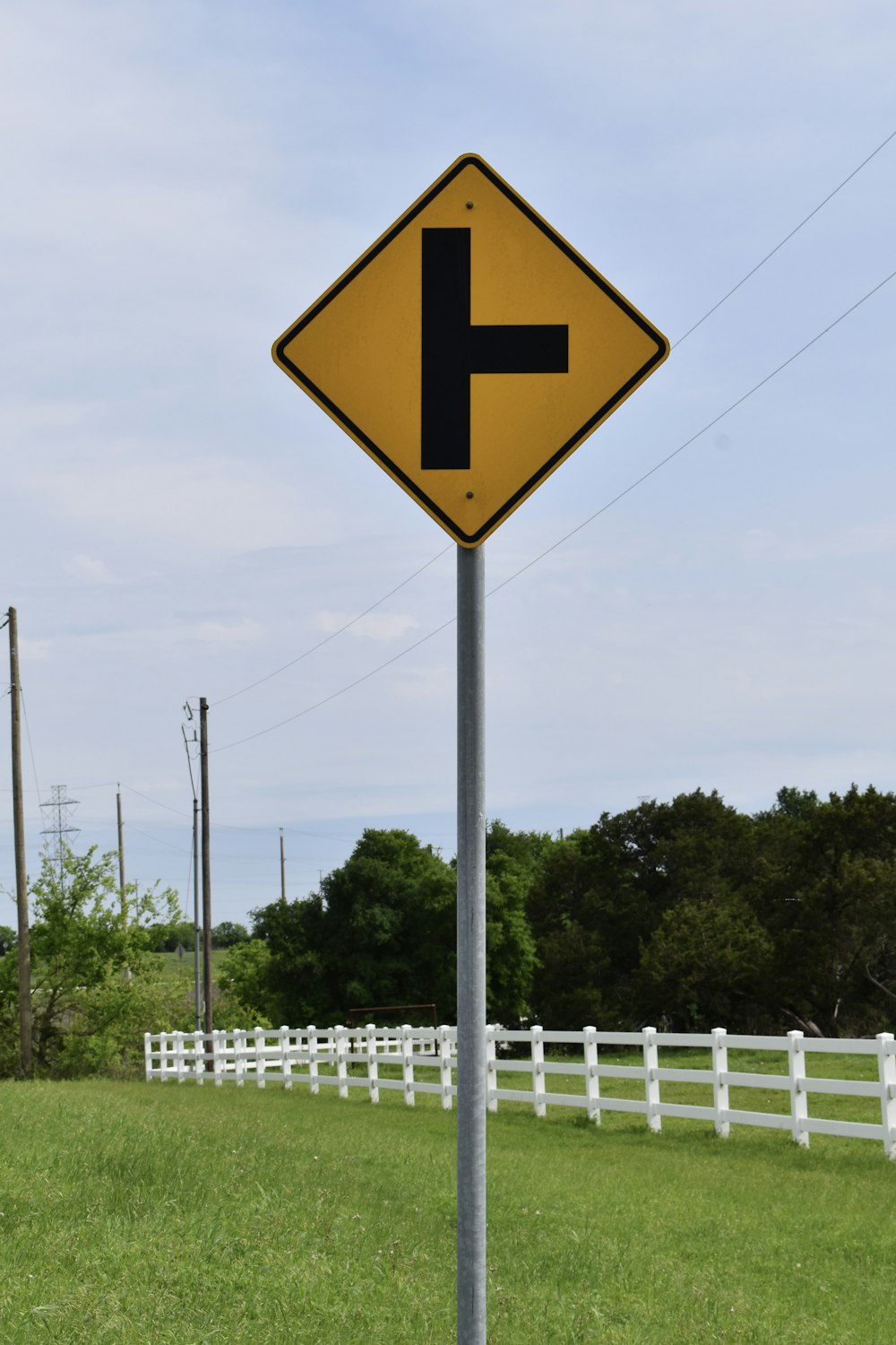 a yellow and black street sign sitting on the side of a road