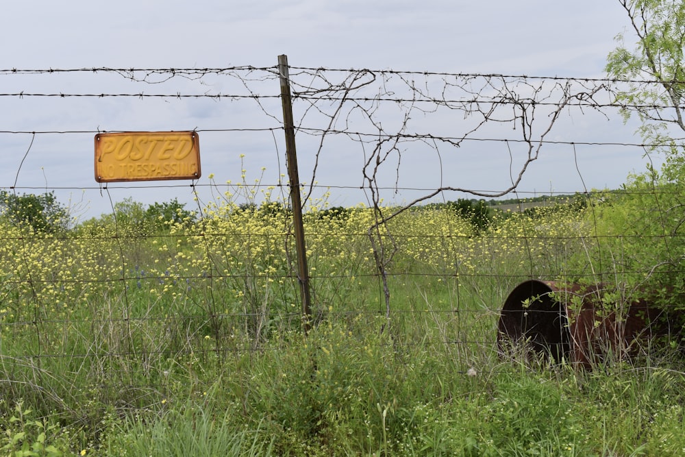 a barbed wire fence with a sign in the background