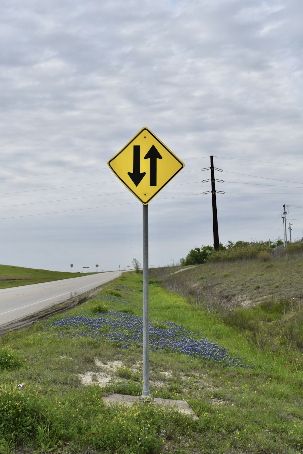 a yellow and black street sign sitting on the side of a road