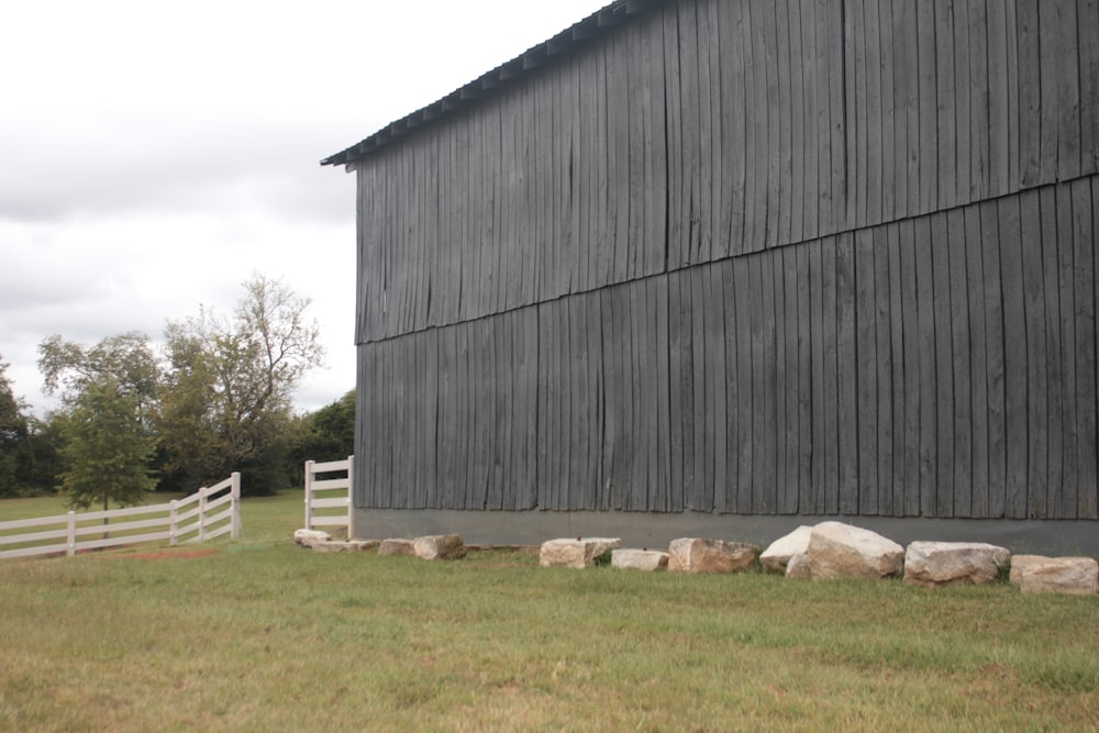 a black barn with a white fence in front of it