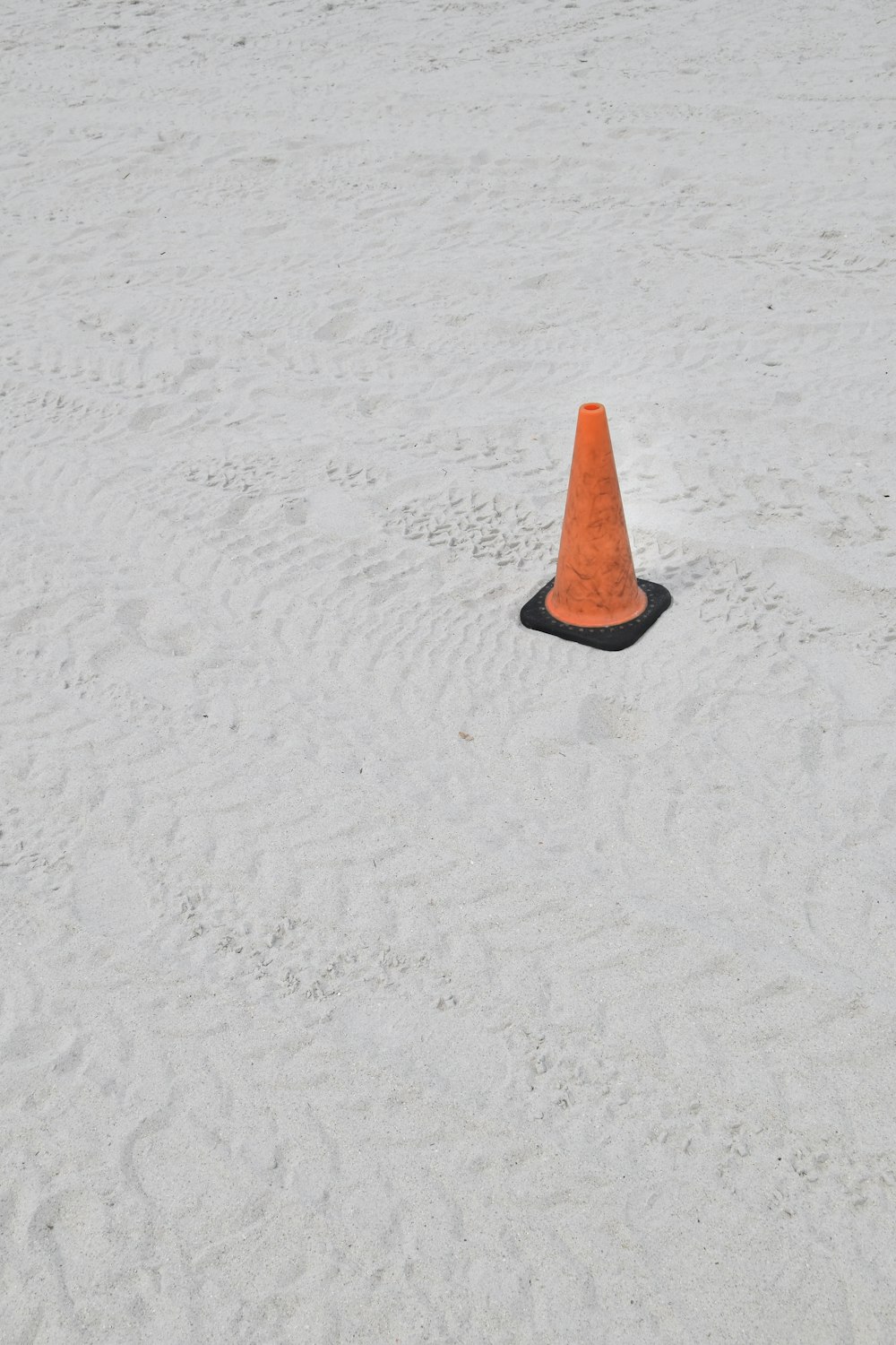 an orange cone sitting on top of a sandy beach