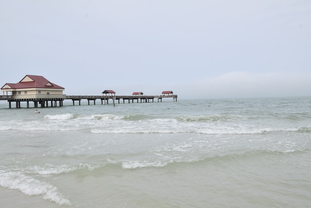 a beach with a pier and houses in the water