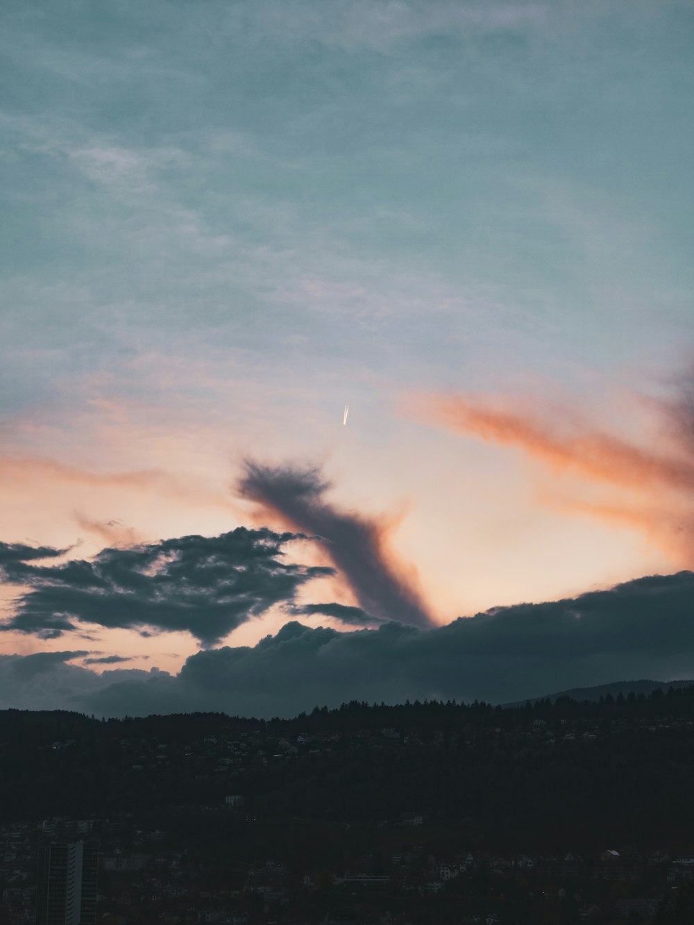 a plane flying through a cloudy sky at sunset