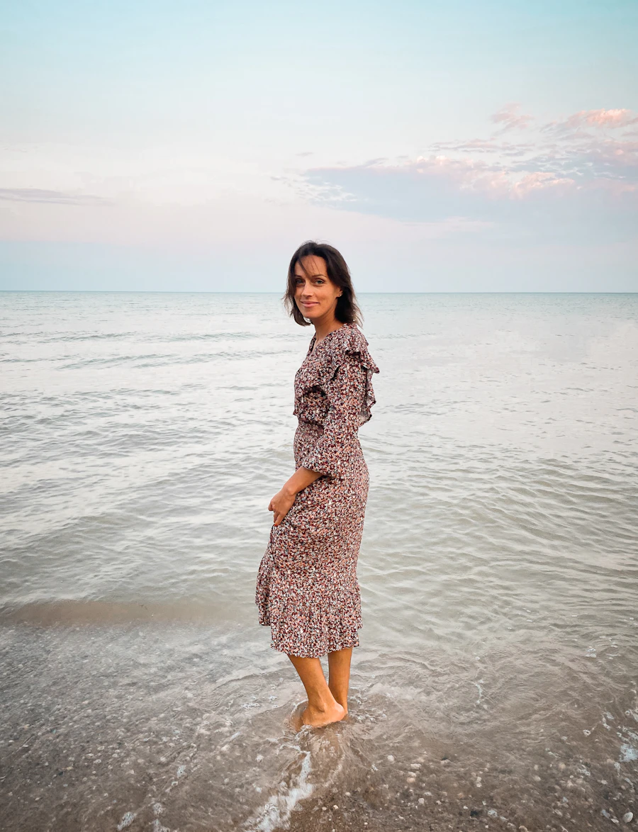 Model wading in shallow sea water in a floral midi dress