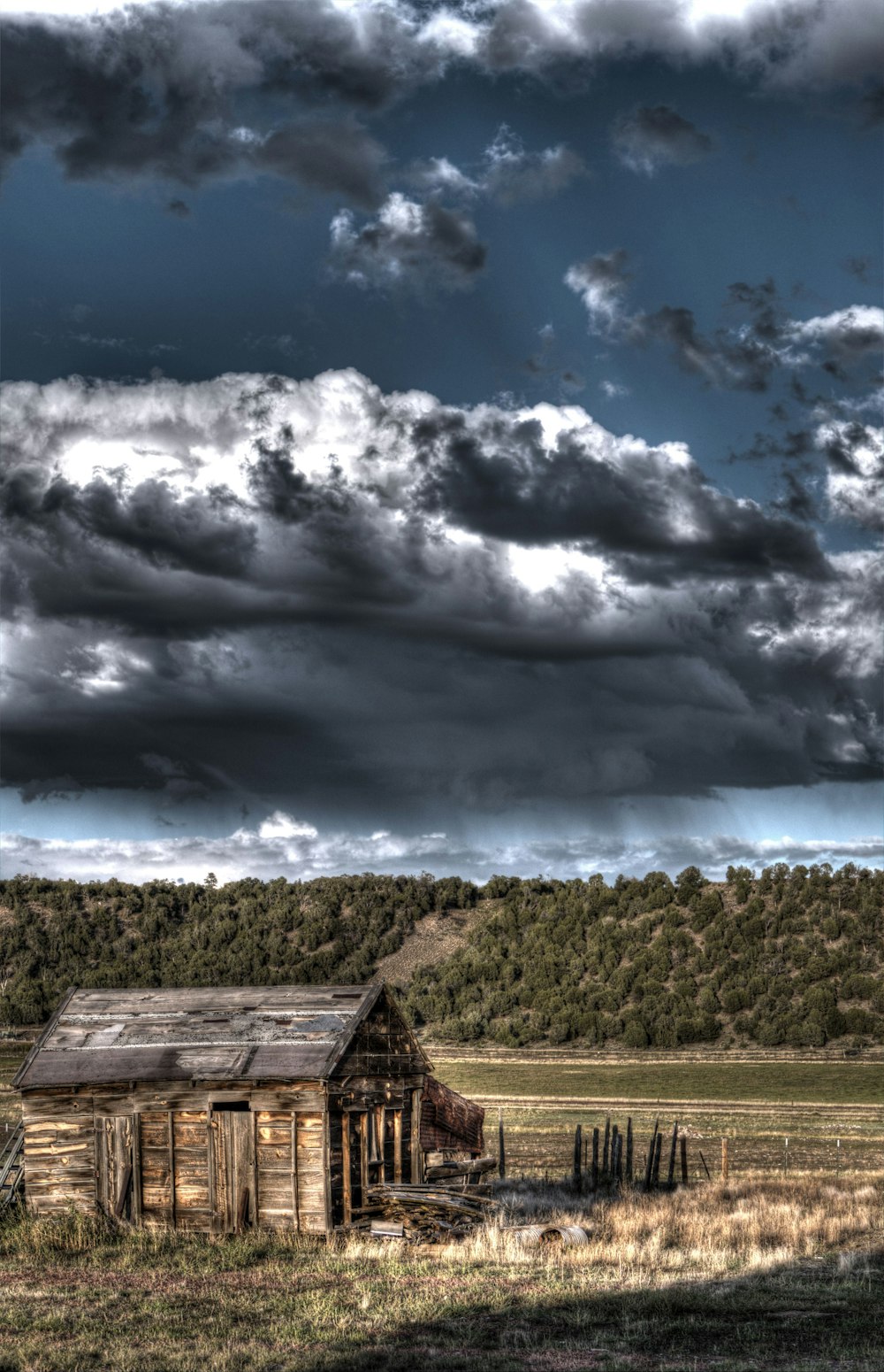 an old wooden building in a field under a cloudy sky