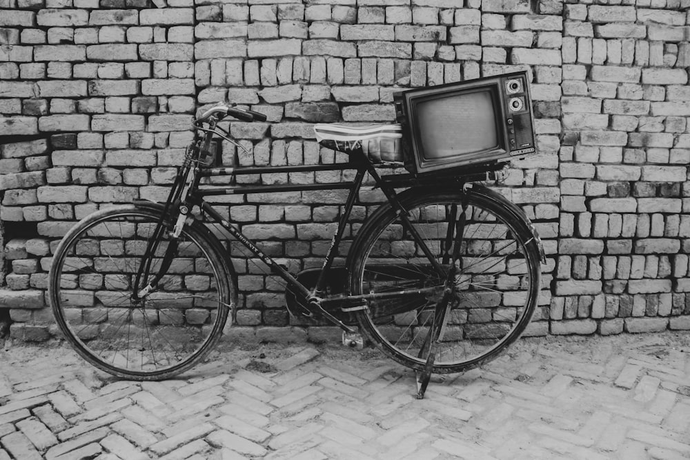 a bicycle parked next to a brick wall