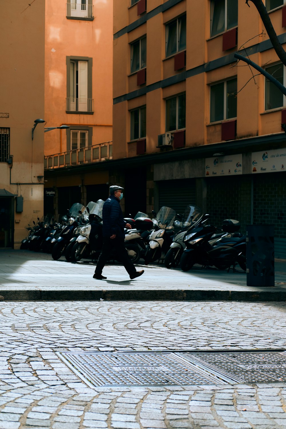 a man walking down a street next to a tall building