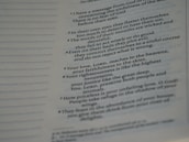 A close-up view of a page from a book presenting text in paragraph form. The text includes numbered points and is slightly blurred towards the edges, indicating shallow depth of field. The page features both bold and regular font styles indicating different emphasis on certain parts.