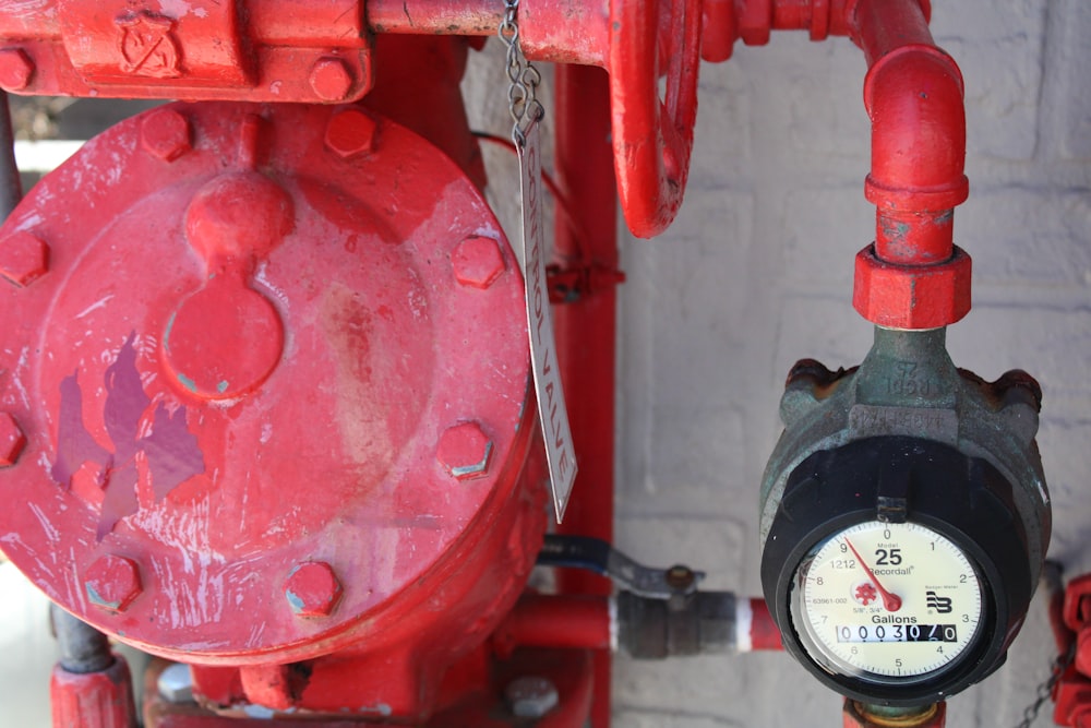 a close up of a red valve with a clock on it