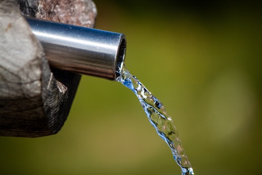 a close up of a metal faucet with water coming out of it