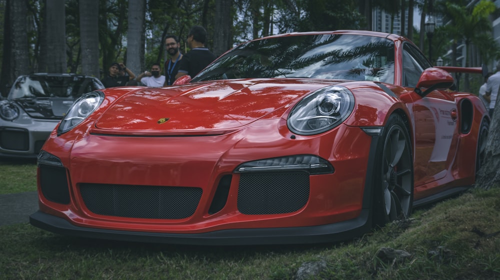 a red sports car parked in front of a group of people
