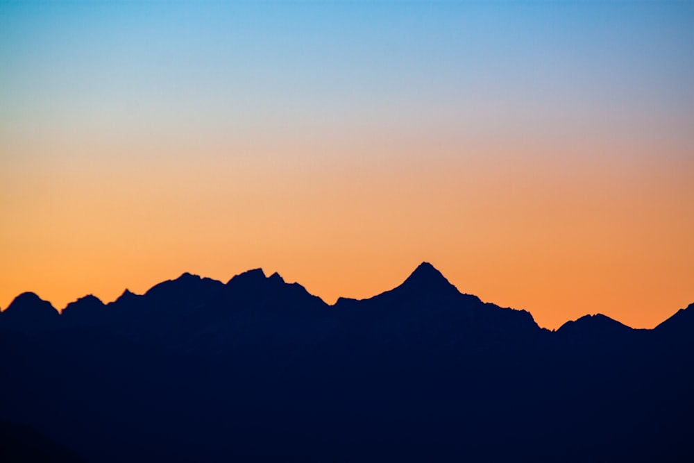 a plane flying over a mountain range at sunset