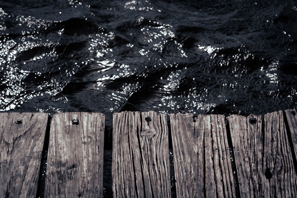 Un primo piano di un molo di legno con l'acqua sullo sfondo