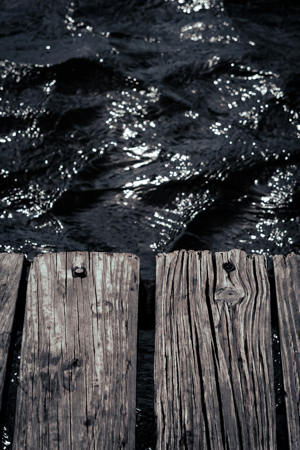 Un primer plano de un muelle de madera con agua de fondo