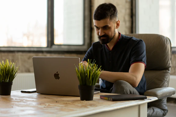 a man sitting at a desk using a laptop computer