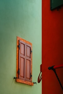 a wooden window on a green wall next to a red wall