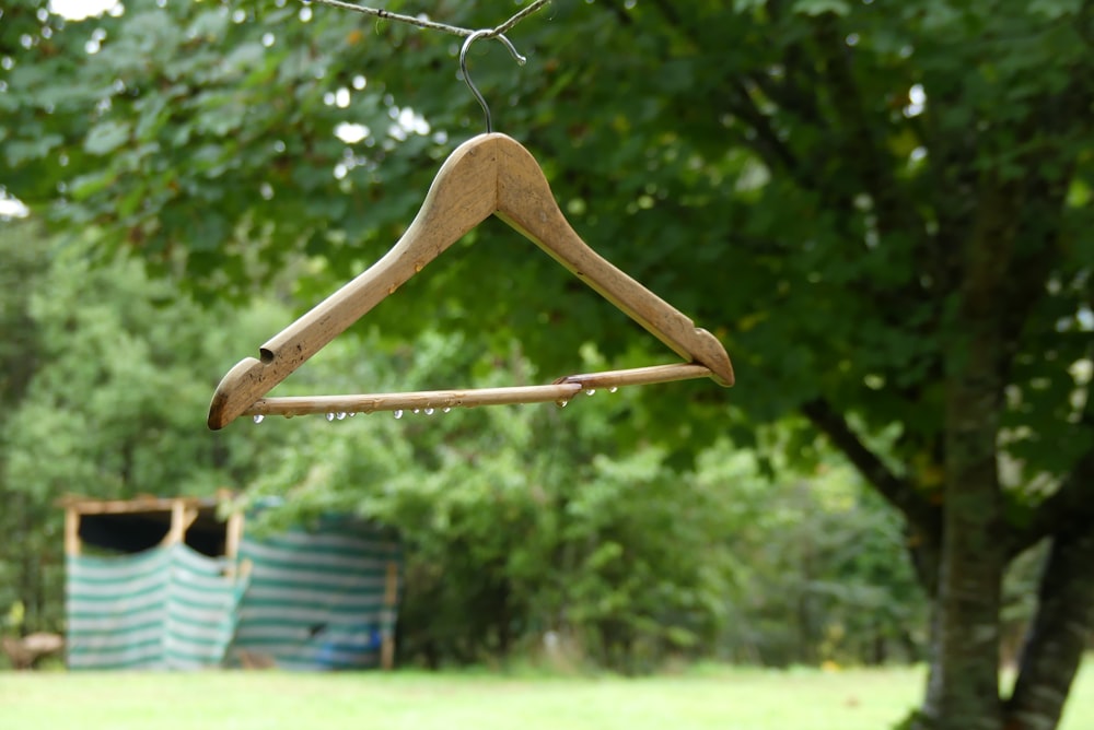 a wooden coat hanger hanging from a tree