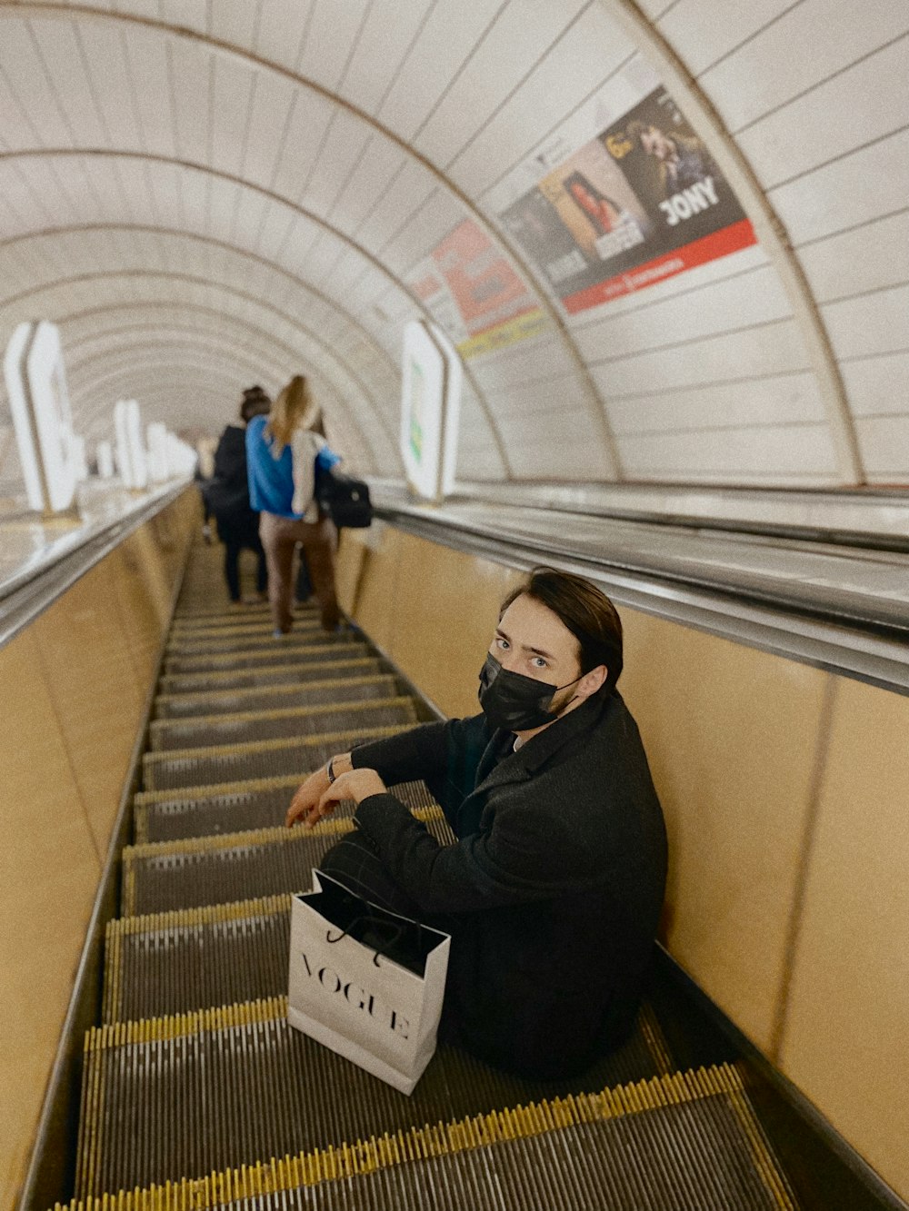 a woman sitting on an escalator with a face mask on