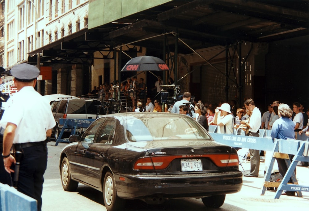 a police officer standing next to a car in front of a crowd of people