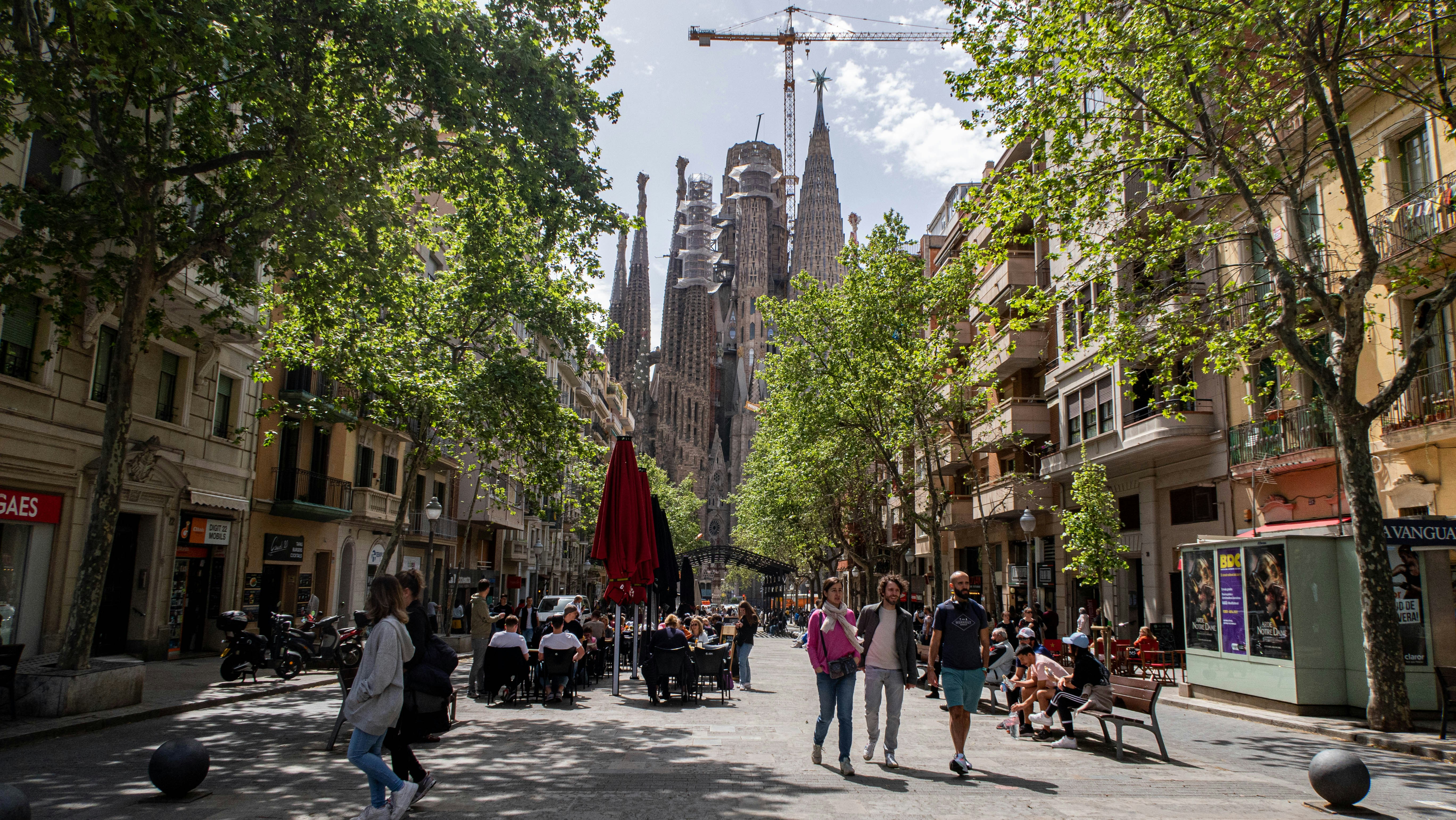 a group of people walking down a street next to tall buildings, 