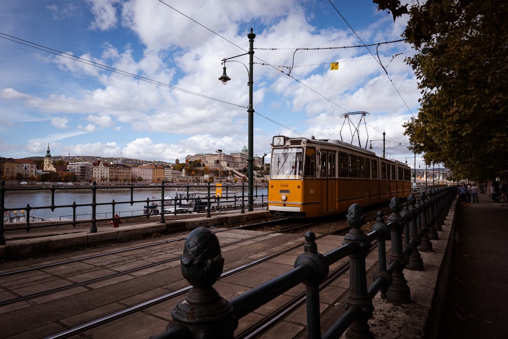 a yellow train traveling down train tracks next to a river