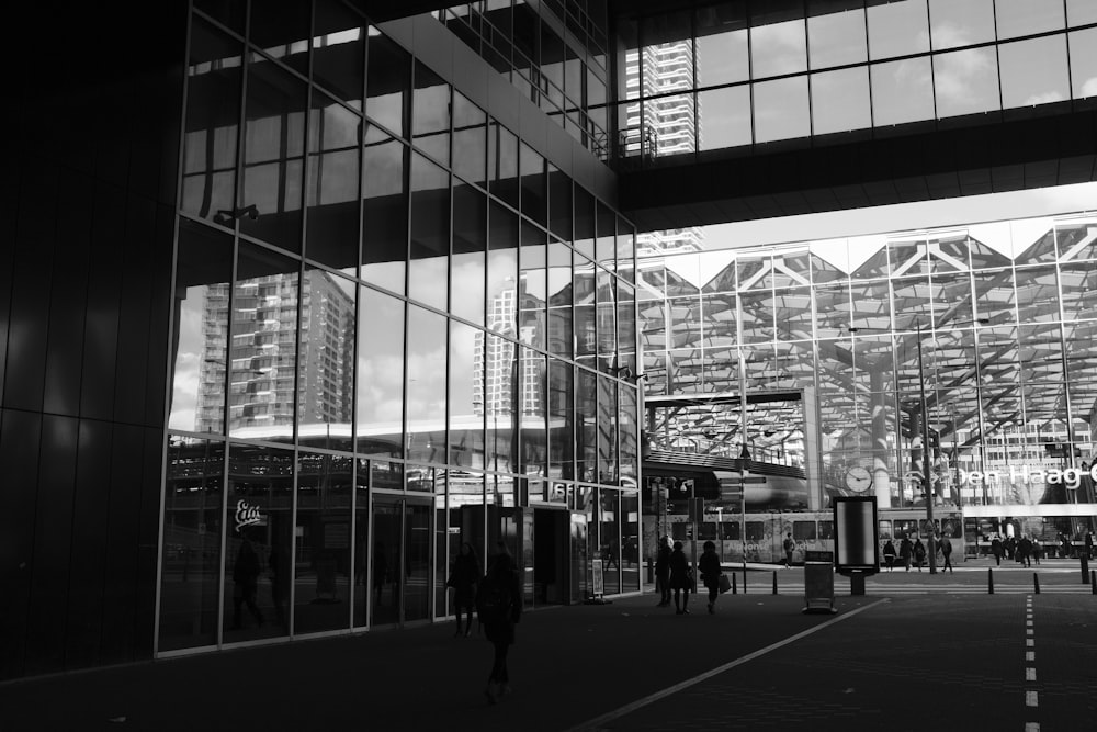 a black and white photo of people walking in front of a building