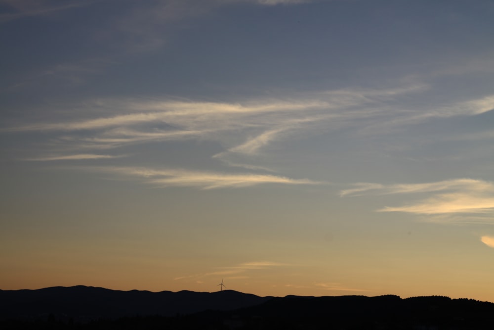 a plane flying in the sky at sunset