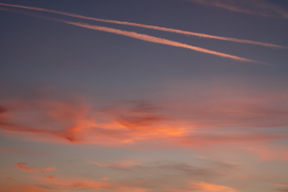 a sunset with contrails in the sky