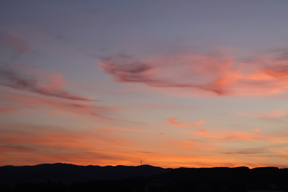 a sunset with clouds and mountains in the background