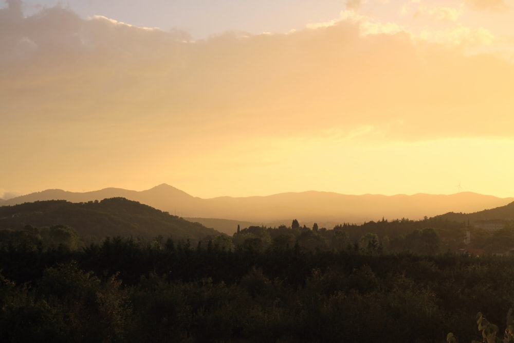 the sun is setting over the mountains in the distance