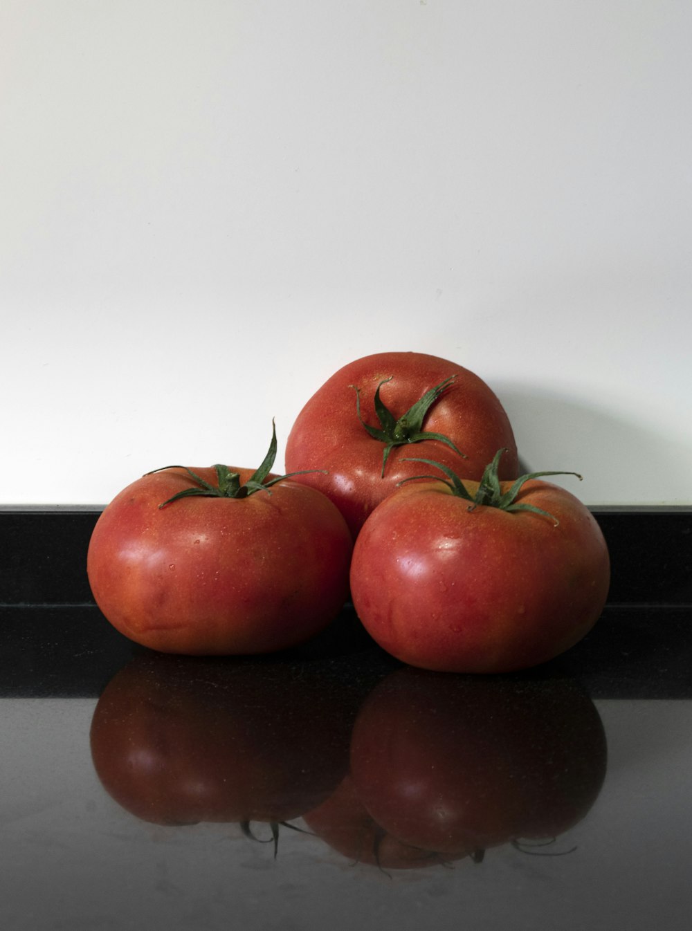 a group of three tomatoes sitting on top of a counter