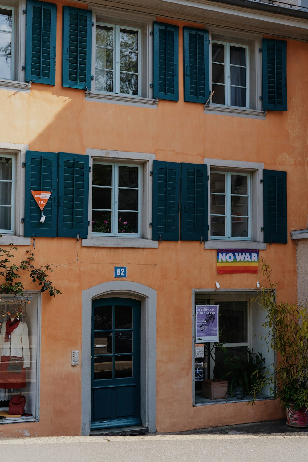 Un edificio arancione con persiane verdi e un cartello di non guerra